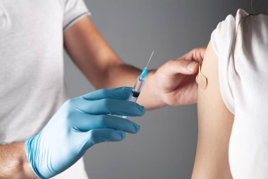 Bir doktor genç bir kıza aşı yapar.