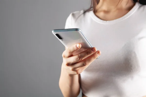 young woman presses the phone screen on a gray background