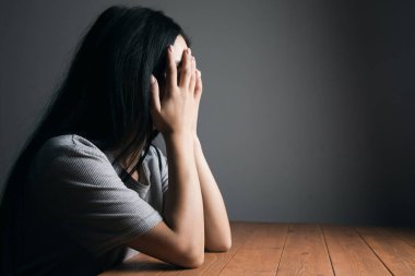 Masada oturup yüzünü kapatan yorgun bir kadın.