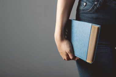 Genç bir kadın elinde bir kitapla ayakta duruyor.