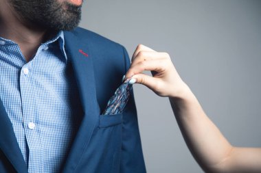 Bir kadın bir erkeğin takım elbisesini düzeltir.