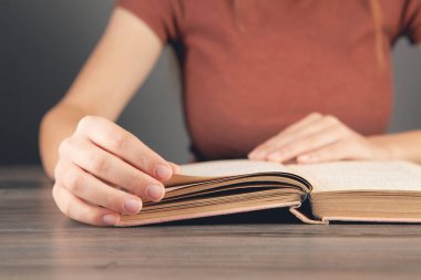 Kız kütüphanede kitap okuyor.