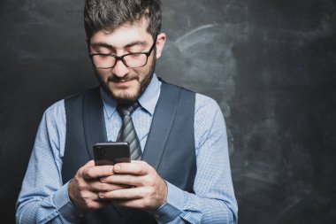 Adam gri arkaplanda telefona bakıyor.