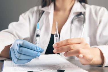 Doktor şırıngayı ve ampulü doldurur.