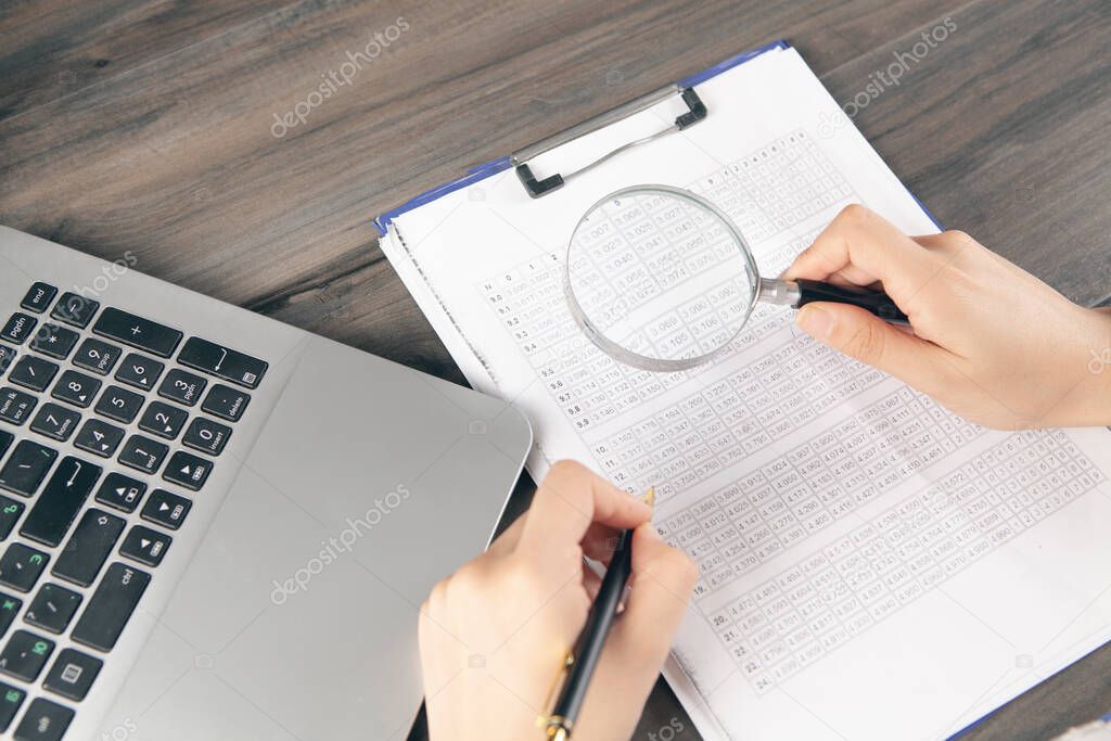 doctor makes notes on papers and looks with a magnifying glass