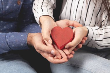 Kadın ve erkek ellerinde bir kalp tutuyorlar.