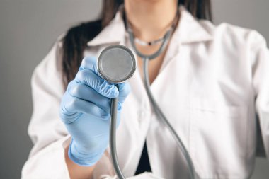 Doktor gri arka planda steteskop tutuyor.