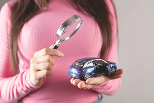 虫眼鏡をかけたおもちゃの車を見ている若い女性は — ストック写真