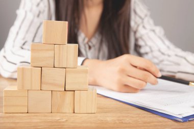 Genç bir kadın küp piramidinin önünde oturuyor.