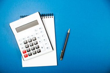mavi arkaplandaki hesap makinesi ve not defteri