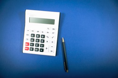 Hesap makinesi ve kalem mavi bir arka plan üzerinde