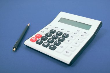 Hesap makinesi ve kalem mavi bir arka plan üzerinde