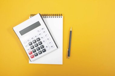 Turuncu arkaplanda hesap makinesi ve not defteri