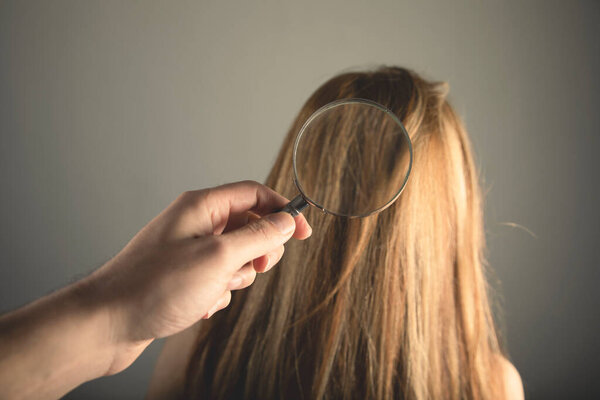 лупа осматривает волосы молодой женщины