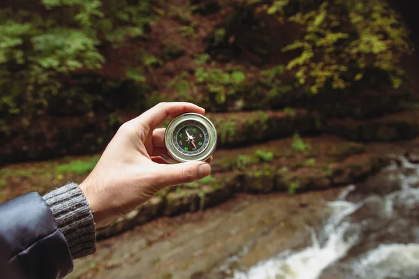 El, nehrin arka planında bir pusula tutuyor.