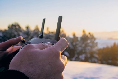 Kışın insansız hava aracından uzaktan kumanda tutan bir adam.