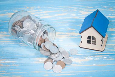 Bozuk paralı bir banka ve masanın üstünde bir ev.