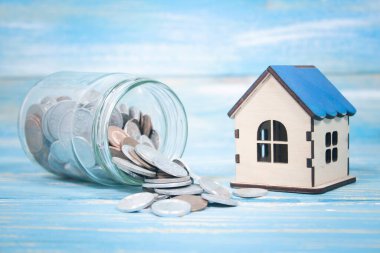 Bozuk paralı bir banka ve masanın üstünde bir ev.