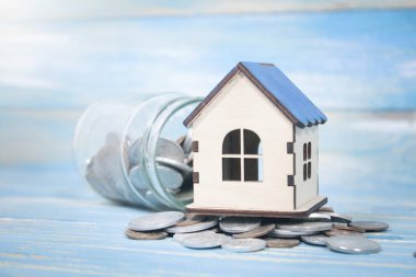 Bozuk paralı bir banka ve masanın üstünde bir ev.