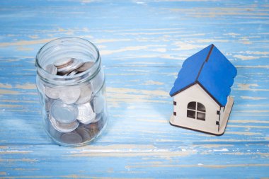 Bozuk paralı bir banka ve masanın üstünde bir ev.