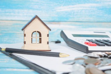 paper, calculator, house and coins on the table