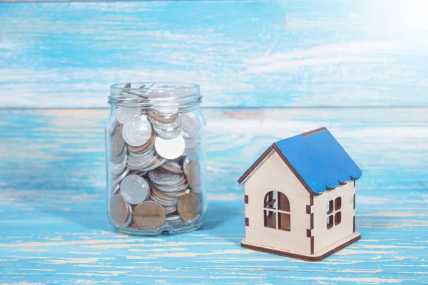 Bozuk paralı bir banka ve masanın üstünde bir ev.