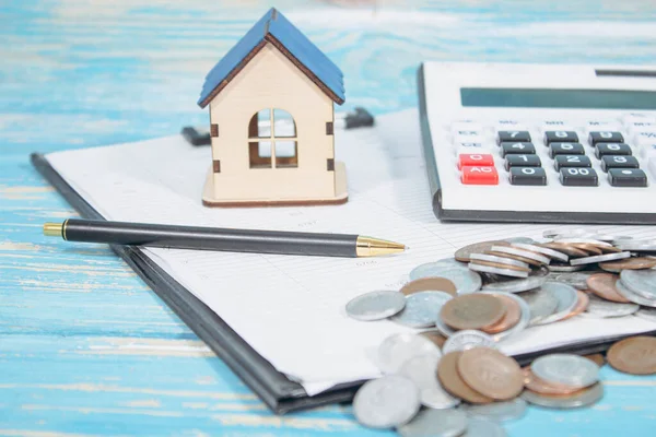 paper, calculator, house and coins on the table