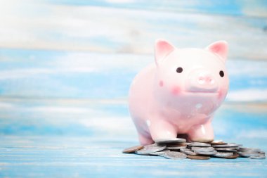 piggy bank stands on a pile of coins