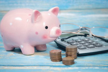 piggy bank and calculator on the table. counting coins. optical glasses.