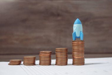 rocket on growing coins on papers
