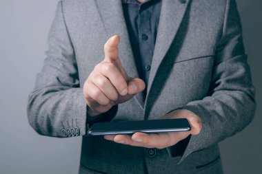 Genç işadamı bir telefon tutuyor ve sanal ekrana tıklıyor.