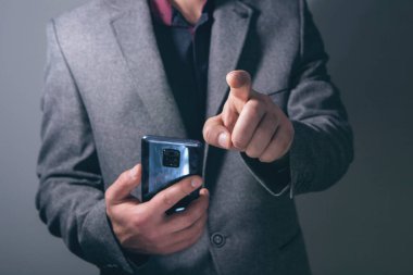 Genç işadamı bir telefon tutuyor ve sanal ekrana tıklıyor.