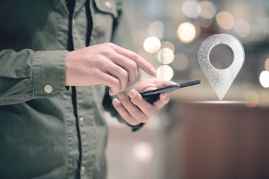 Web ve noktalardan GPS simgesi. Elinde telefon tutan bir adam.