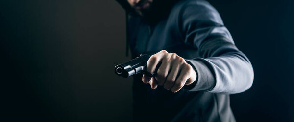 a man holding a pistol on a dark background