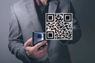QR kod simgesini tara. QR kodunun dijital taraması. Adam, telefonu elinde tutarak ekrana baskı yapıyor.