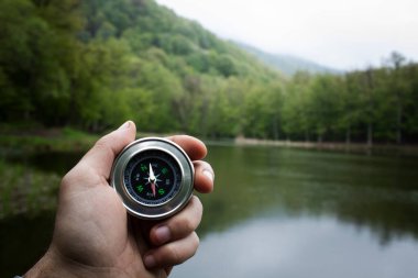 Bir orman gölünün arka planında pusula