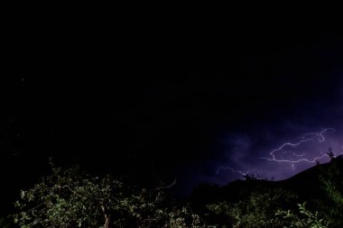 Ormanın üzerinde gece gökyüzünde şimşekler çakıyor