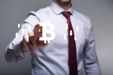 Yukarı ve aşağı okları olan Bitcoin simgesi. Ekranda tıklayan adam