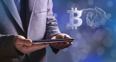 El ağdan Bitcoin 'e tıklıyor. Elinde tablet tutan bir adam.