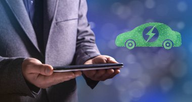 Şebekeden elektrikli araba. Elinde tablet tutan bir adam.