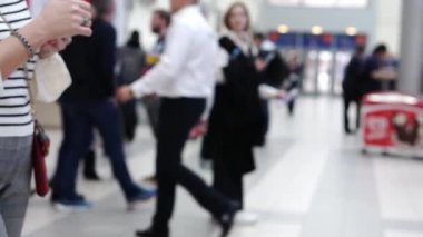 Büyük, parlak bir iş merkezi lobisinde bir grup insan..