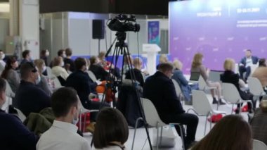 Tripodu olan bir video kamera konferans odasındaki hoparlörleri yakalıyor..