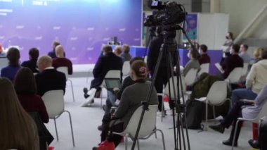 Tripodu olan bir video kamera konferans odasındaki hoparlörleri yakalıyor..