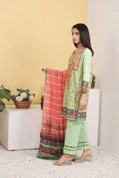 A Pakistani shalwar kameez suit with dupatta. Pakistani model is shown her dress with style.