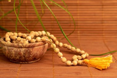 Seramik kasede tahta mala boncukları. Fotokopi alanı için ahşap arka planda yeşil yapraklar var. Farkındalık ve Japon meditasyon konsepti