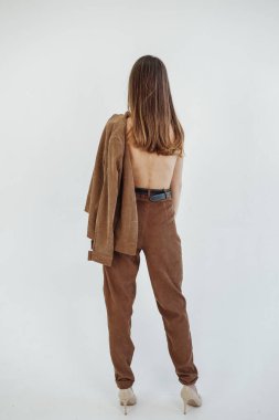 Stüdyodaki bir fotoğraf çekiminde kahverengi takım elbiseyle poz veren güzel bir manken.