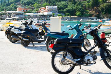 Parked mopeds on the seashore, waiting for people. People left mopeds and went to the sea.