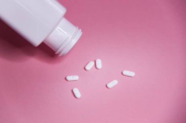 Pembe arka planda beyaz haplar