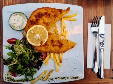 Salatayla servis edilen tavuk şnitzel menüsü. Akşam yemeği beyaz bir tabakla servis edildi..