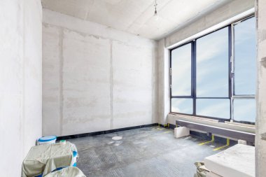 Beton duvarları ve beyaz odadaki büyük pencereden mavi Claudy gökyüzü manzaralı inşaat alanı. Boş modern ışık odası tamirat altında.